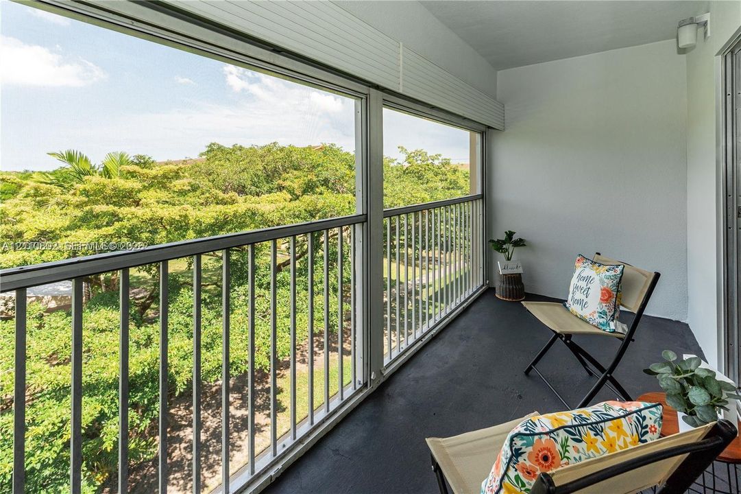 Covered balcony featuring metal railings, sliding glass window panels, and wall-mounted lighting