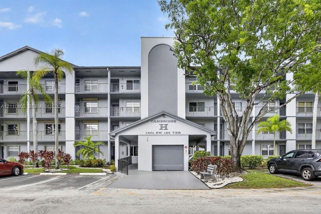 Multi-story exterior building featuring a covered entryway, private balconies, and mature landscaping