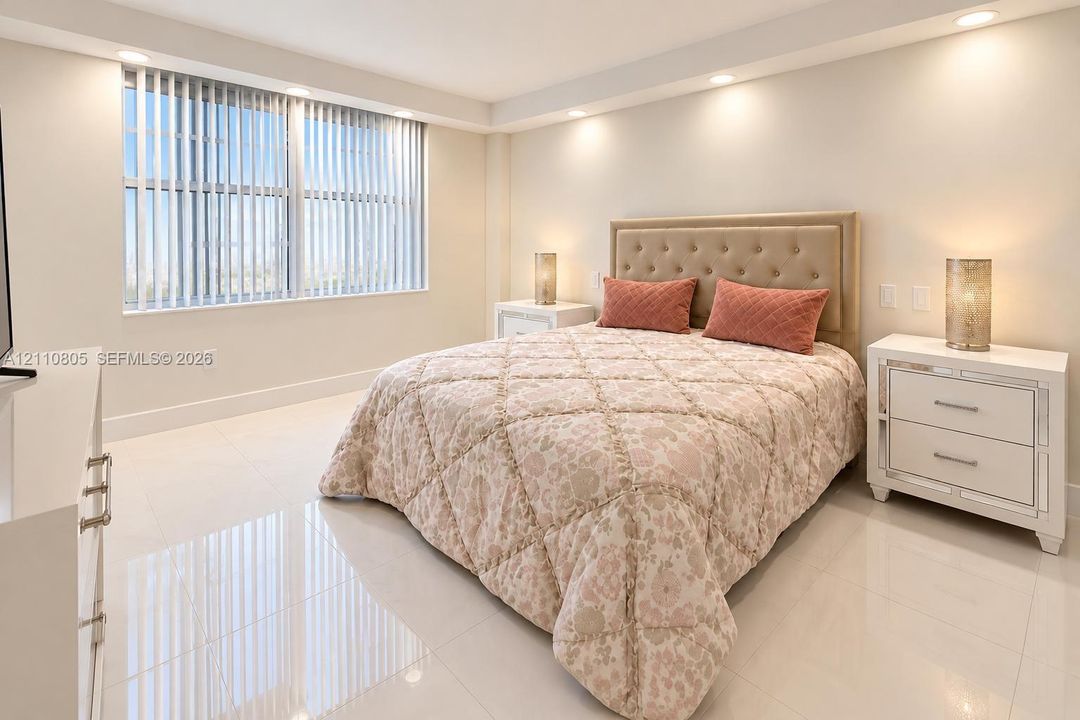 Large-format tile flooring, recessed ceiling lighting, and expansive window with vertical blinds