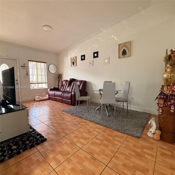 Living area featuring wood-finish tile flooring, crown molding, and a multi-pane window