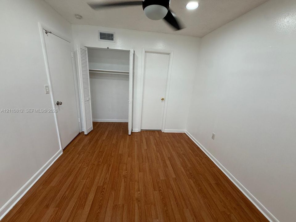 Interior room featuring wood-finish flooring, a closet with louvered double doors, a ceiling-mounted light fixture, and recessed ceiling lighting