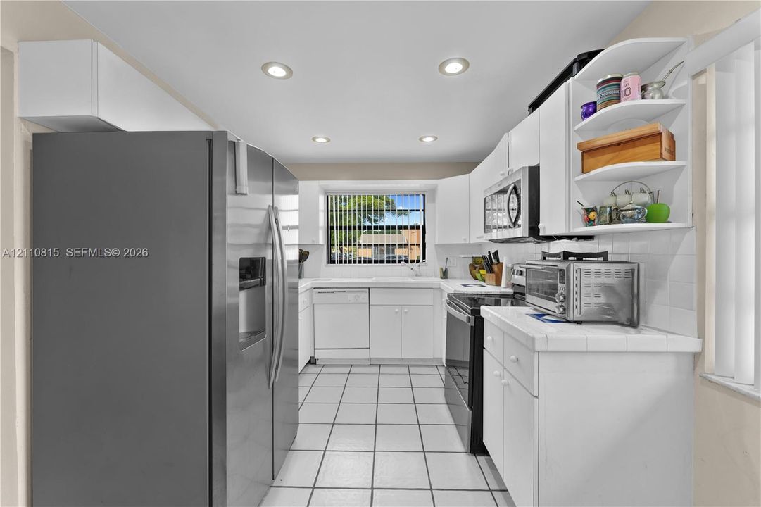 Kitchen featuring white cabinetry, stainless steel appliances, ceramic tile flooring, and recessed ceiling lighting