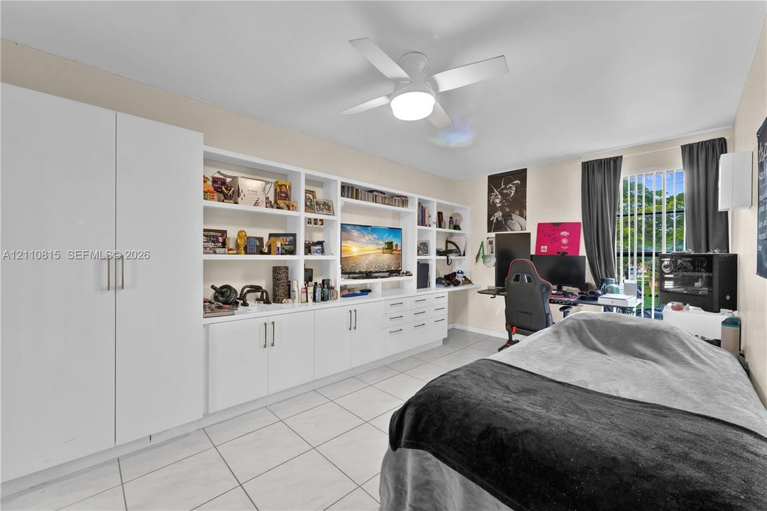 Wall-to-wall built-in cabinetry featuring white shaker-style doors, open display shelving, and integrated drawers, complete with tile flooring and a ceiling-mounted light fixture