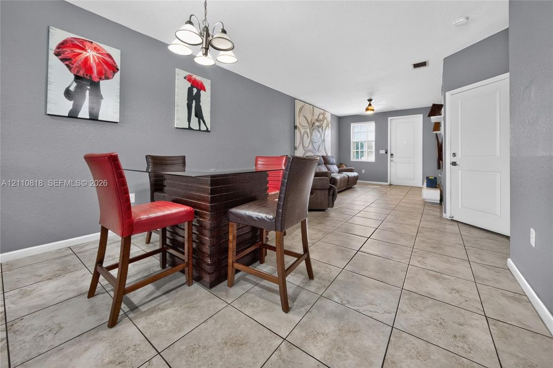 Neutral-toned ceramic tile flooring, multi-light chandelier fixture, and white interior doors