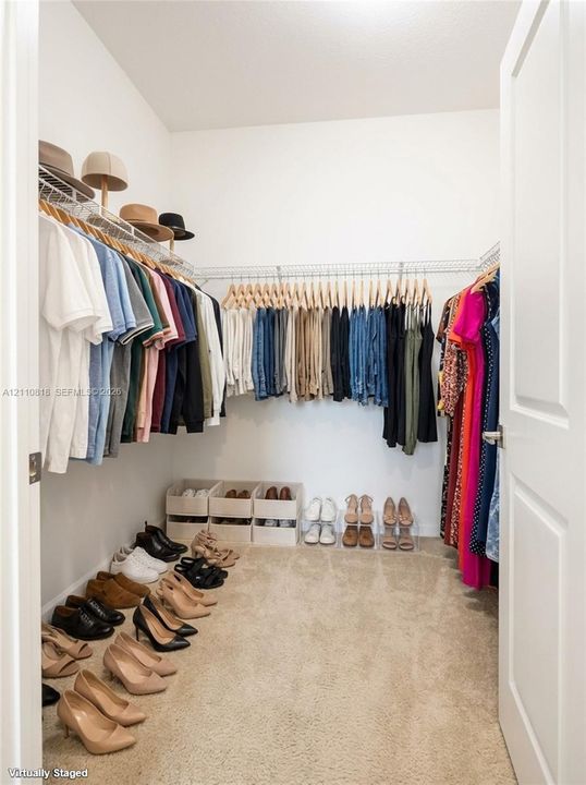 Walk-in storage space featuring wall-to-wall wire shelving and neutral carpeting