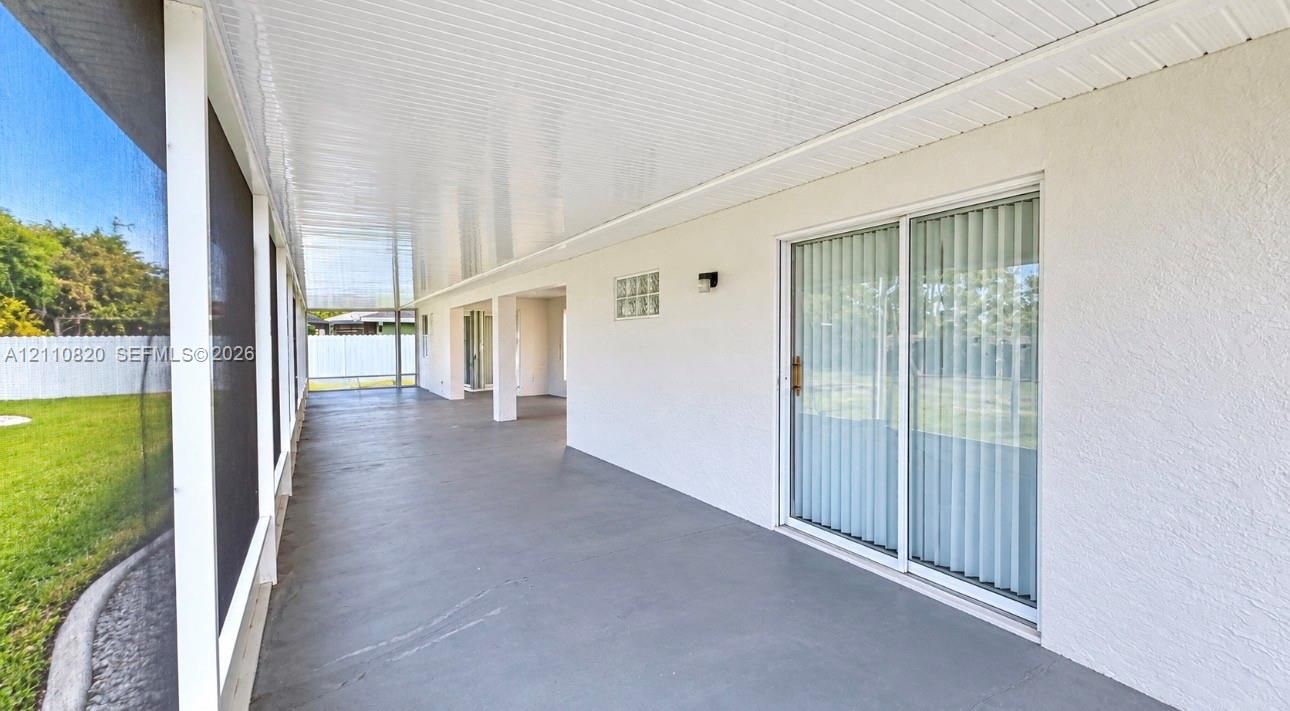 Screened-in lanai featuring a concrete floor, covered ceiling, glass block accent window, and sliding glass door