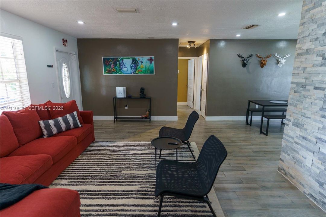 Open-concept area featuring stone-clad accent wall, recessed lighting, and wood-finish flooring
