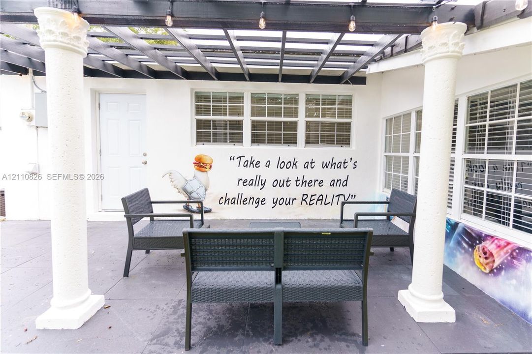Patio area featuring a dark-toned pergola, decorative columns, and multi-pane windows
