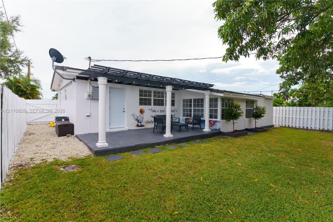 Exterior patio featuring a pergola with classic columns, concrete surfacing, fenced yard, and gravel side path