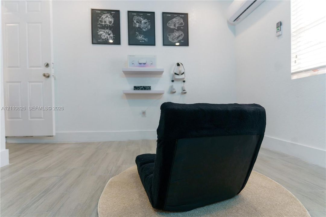 Wood-finish flooring, two wall-mounted floating shelves, white six-panel interior door, and wall-mounted climate control unit