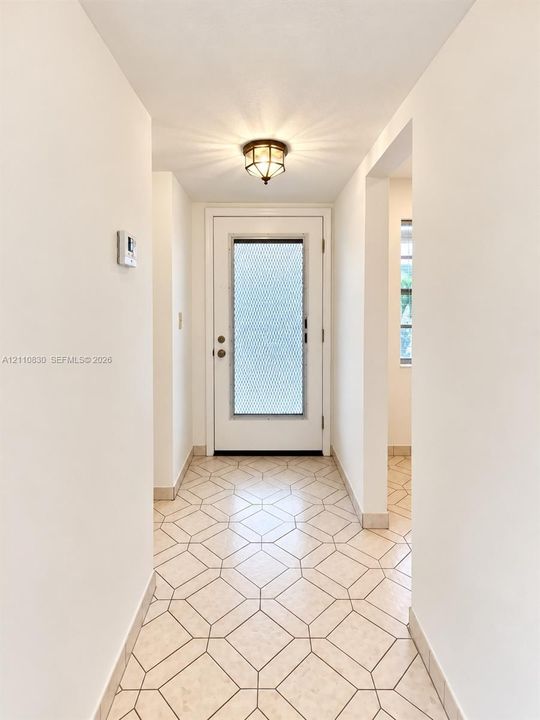 Entryway featuring geometric patterned tile flooring, a door with a metal security screen, and a flush-mount overhead light fixture