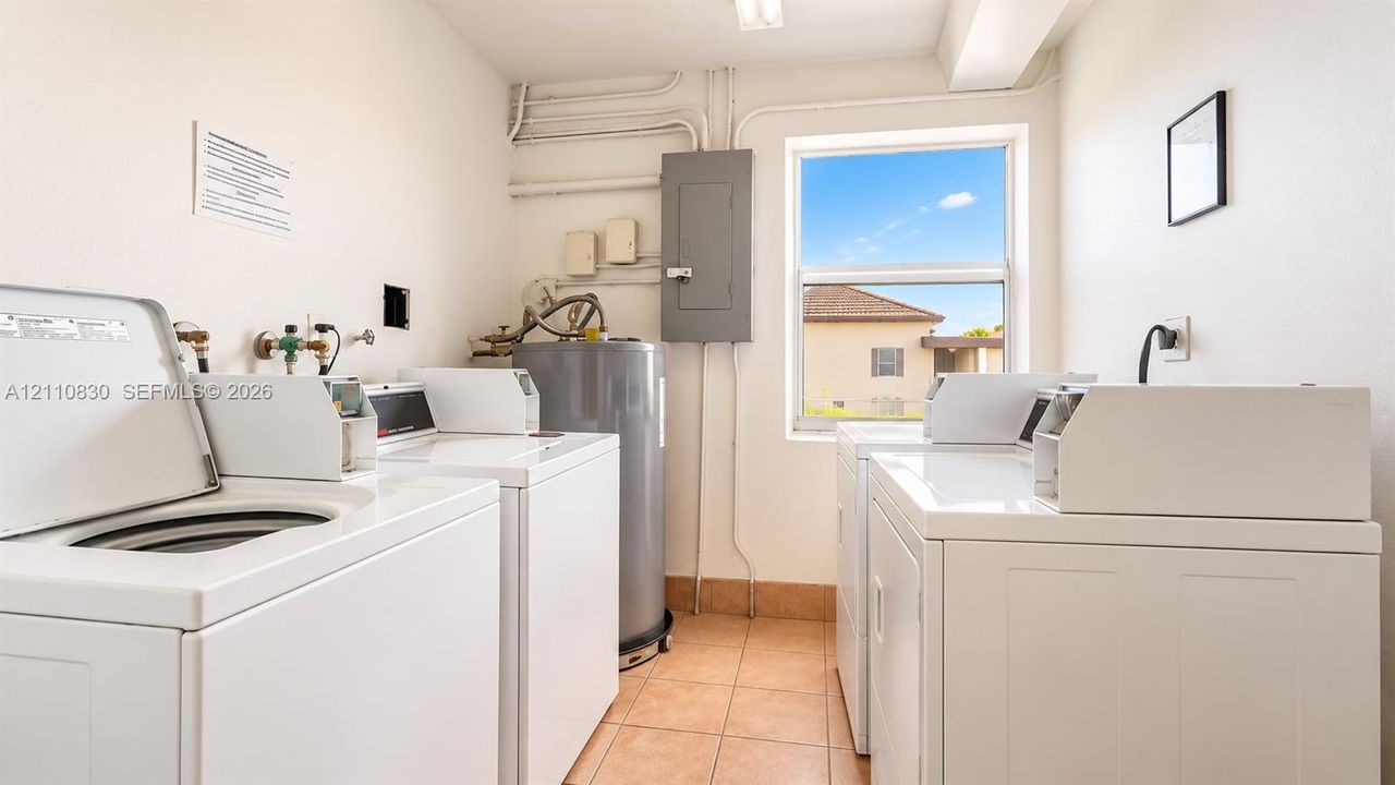 Dedicated laundry room featuring side-by-side washer and dryer units, terracotta tile flooring, ample cabinetry and storage, and abundant natural light from large window with scenic desert views