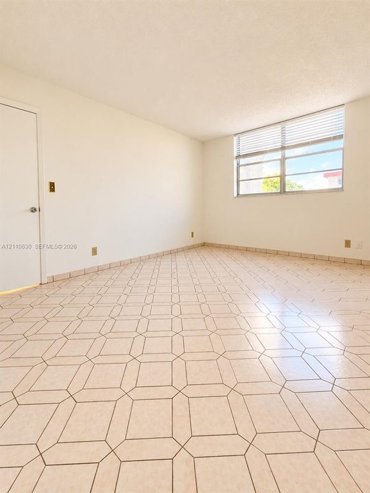 Neutral-toned geometric tile flooring and expansive single-pane window featuring horizontal blinds