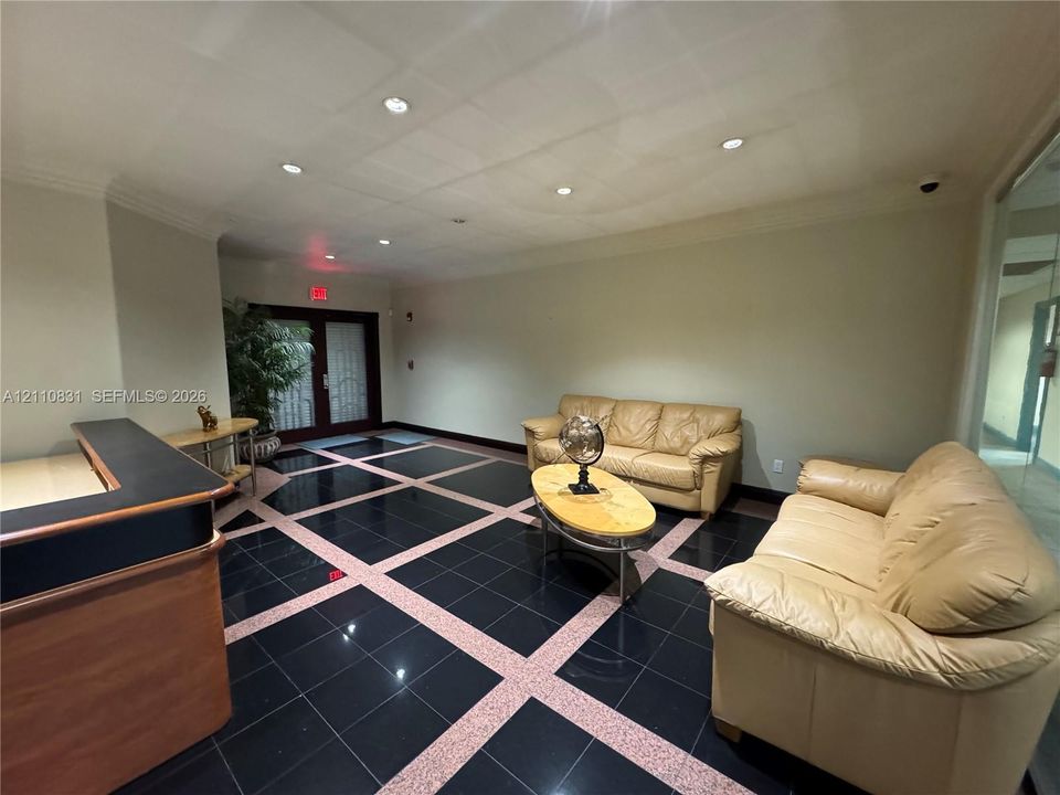 Lobby area featuring black tile flooring with stone grid accents, recessed ceiling lighting, and a built-in reception counter