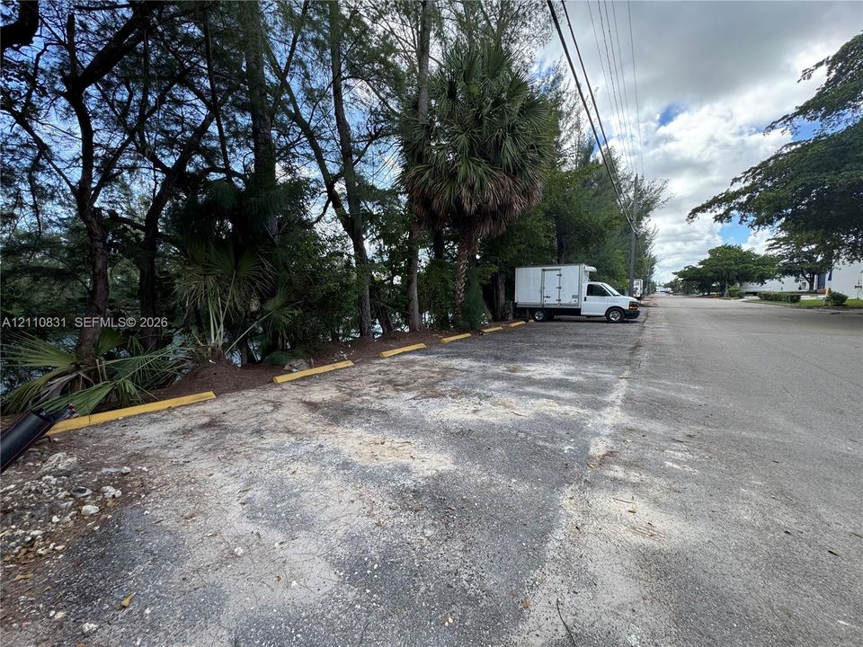 Paved parking area with concrete wheel stops and established mature trees