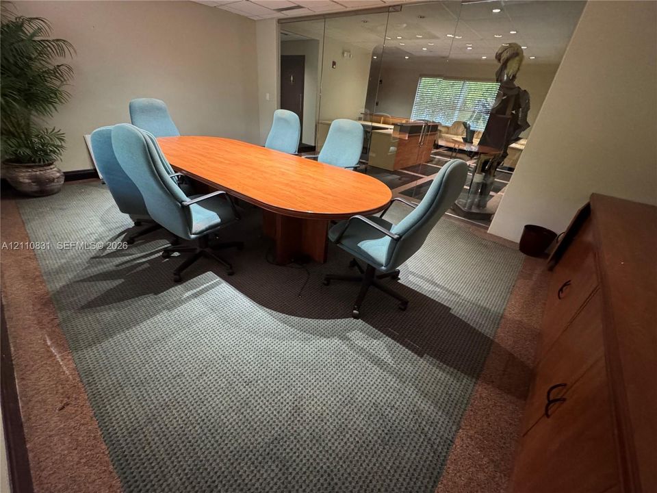 Conference room featuring a glass-partition wall, wood-finish cabinetry, and inset patterned carpet flooring