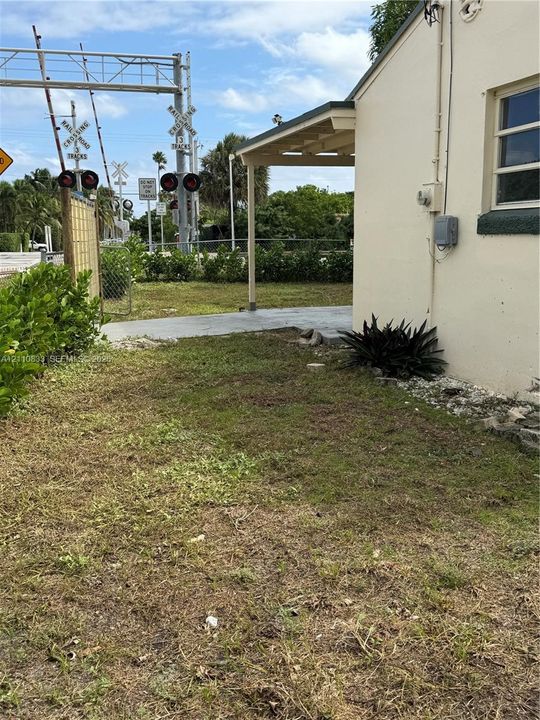 Exterior side yard featuring a concrete patio, covered porch area, and perimeter shrubbery