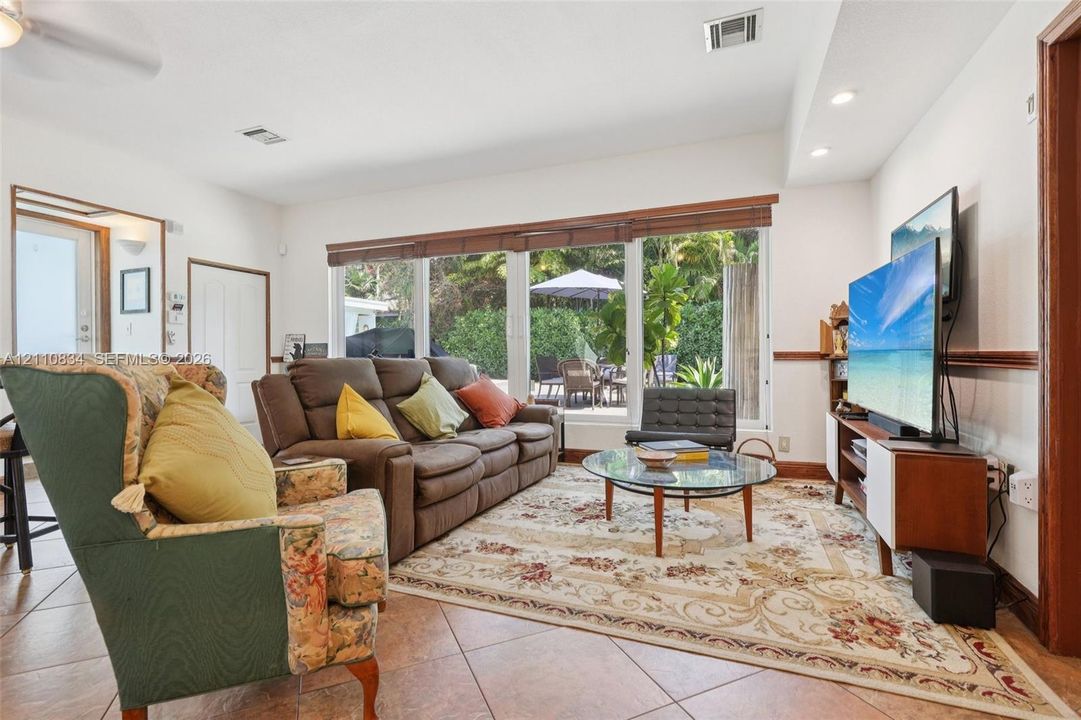 Living area featuring large-format ceramic tile flooring, recessed lighting, and a panoramic window wall with wood-slat blinds