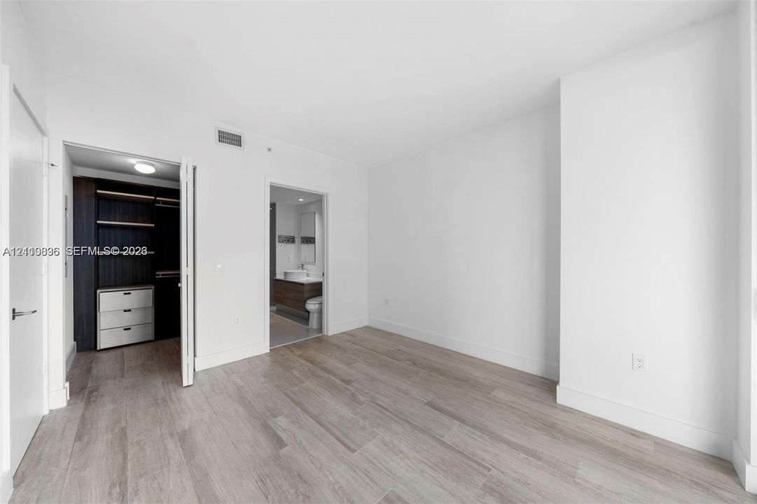 Room featuring wood-finish flooring, built-in closet cabinetry, and a vanity with a vessel sink