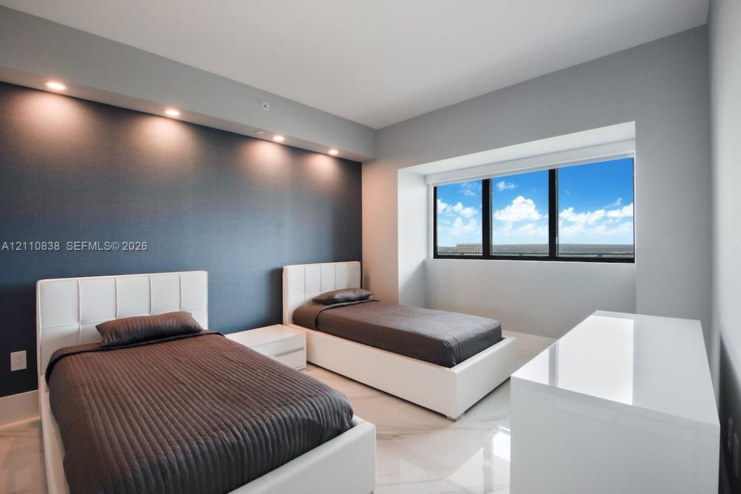 Accent wall with recessed overhead lighting, large-format polished flooring, and expansive windows