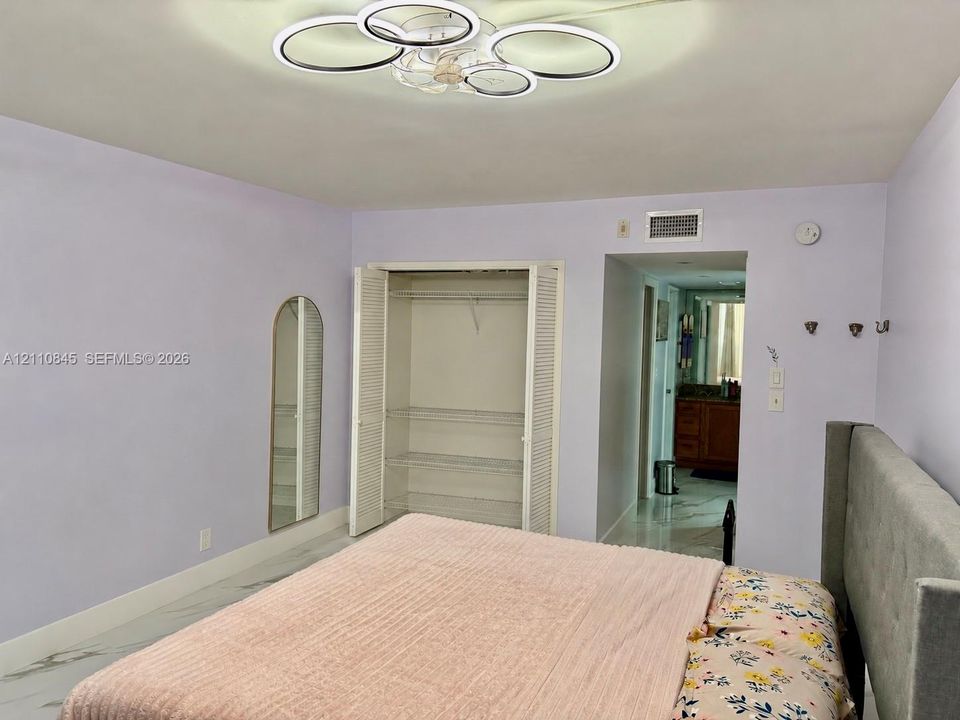 Multi-ring LED flush-mount fixture, closet with louvered bi-fold doors and integrated shelving, and large-format tile flooring