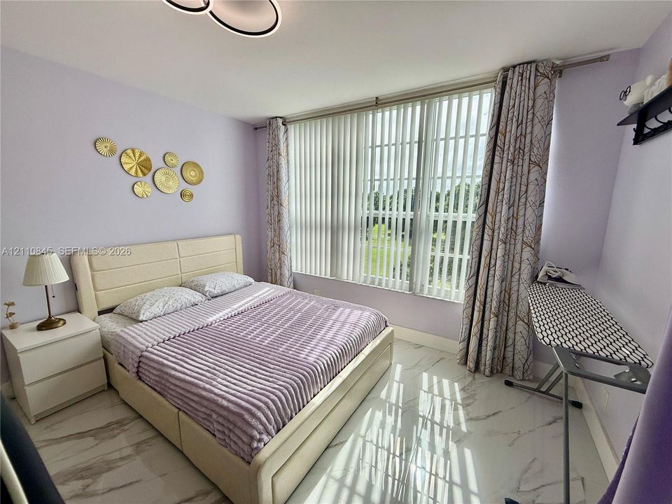 Large floor-to-ceiling windows with vertical blinds, stone-finish flooring, and modern geometric ceiling fixture