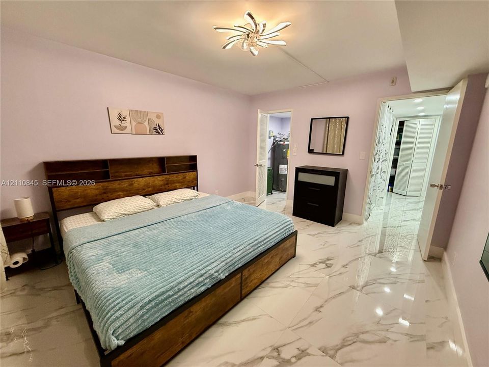 Polished large-format tile flooring with marble-pattern veining, contemporary multi-blade ceiling fixture, and louvered bifold closet doors