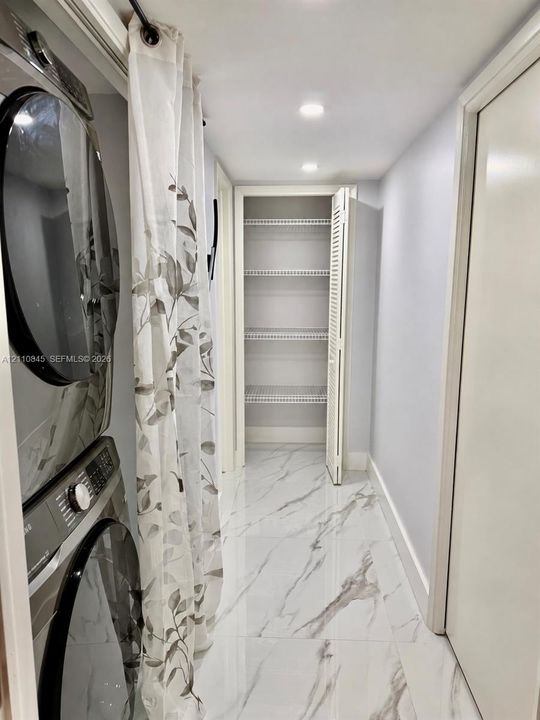 Utility space featuring large-format stone-look porcelain tile flooring, recessed ceiling lighting, and a built-in closet with ventilated wire shelving