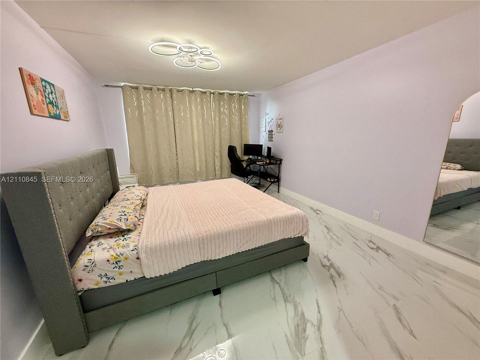 Large-format tile flooring with a veined pattern, arched doorway, and contemporary circular LED flush-mount lighting