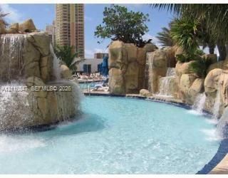 Swimming pool featuring naturalistic rock formations, multiple integrated waterfalls, and tropical landscaping