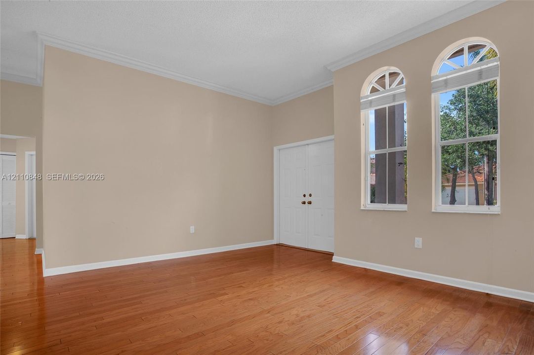 High-ceiling interior featuring wood-finish flooring, dual arched windows, and double door entry