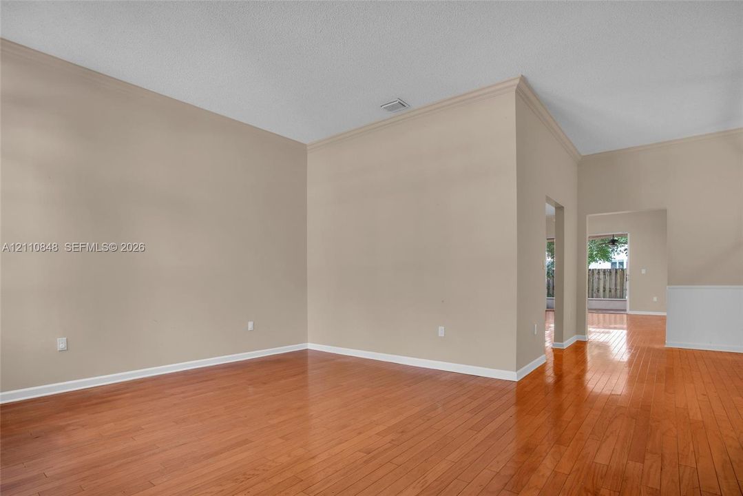 High ceilings featuring crown molding, neutral wall finishes, and polished wood-finish flooring