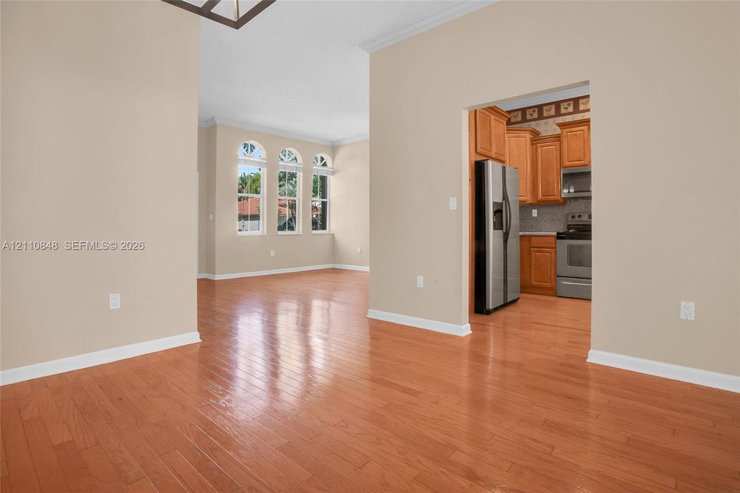 Wood-finish flooring, high ceilings, triple-arched windows, and kitchen cabinetry with built-in stainless steel appliances