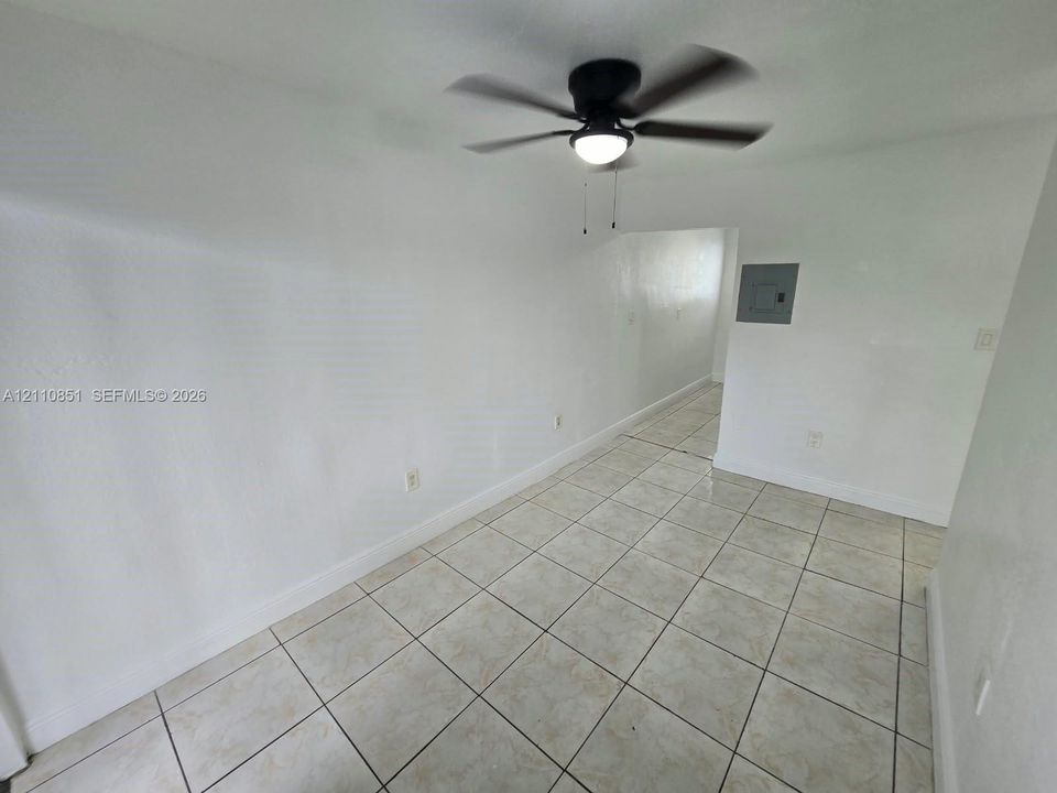 Neutral wall finishes, large-format tile flooring, and a matte black ceiling fan with integrated lighting