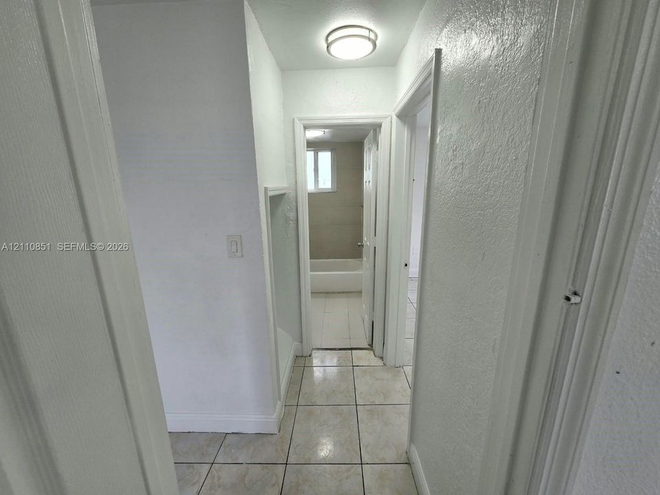 Hallway featuring neutral tile flooring, smooth-finish walls, and a recessed wall niche