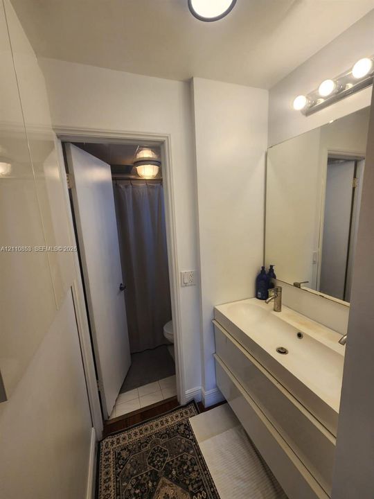 Wall-mounted vanity featuring dual drawers, an integrated sink basin, chrome-finish faucet, and a large, full-width mirror with a three-bulb vanity light fixture