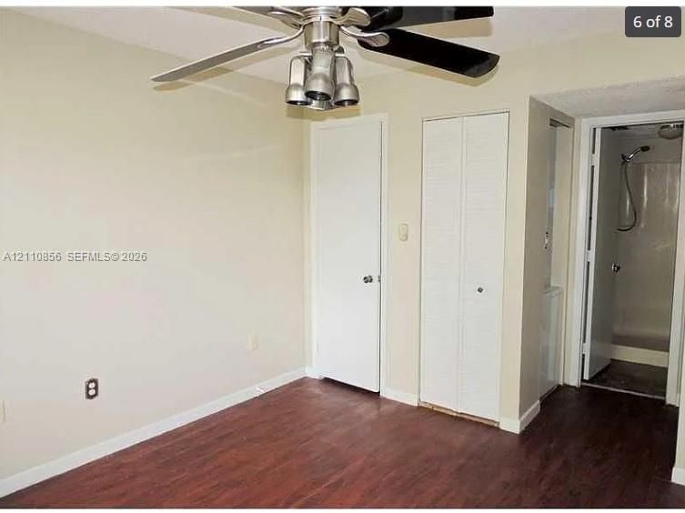 Room featuring wood-finish flooring, ceiling fan with integrated lighting, and bi-fold closet doors