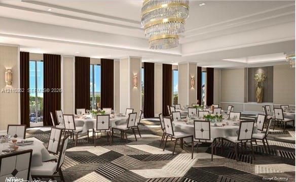 Expansive hall featuring tiered crystal chandelier lighting, recessed ceiling detailing, geometric-patterned carpeting, and floor-to-ceiling windows