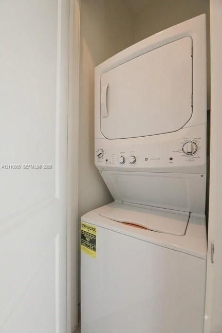 Stacked white laundry unit with dial controls and enclosed alcove setting