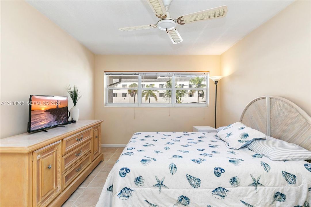 Neutral wall tones, horizontal sliding windows, tile flooring, and a ceiling fan