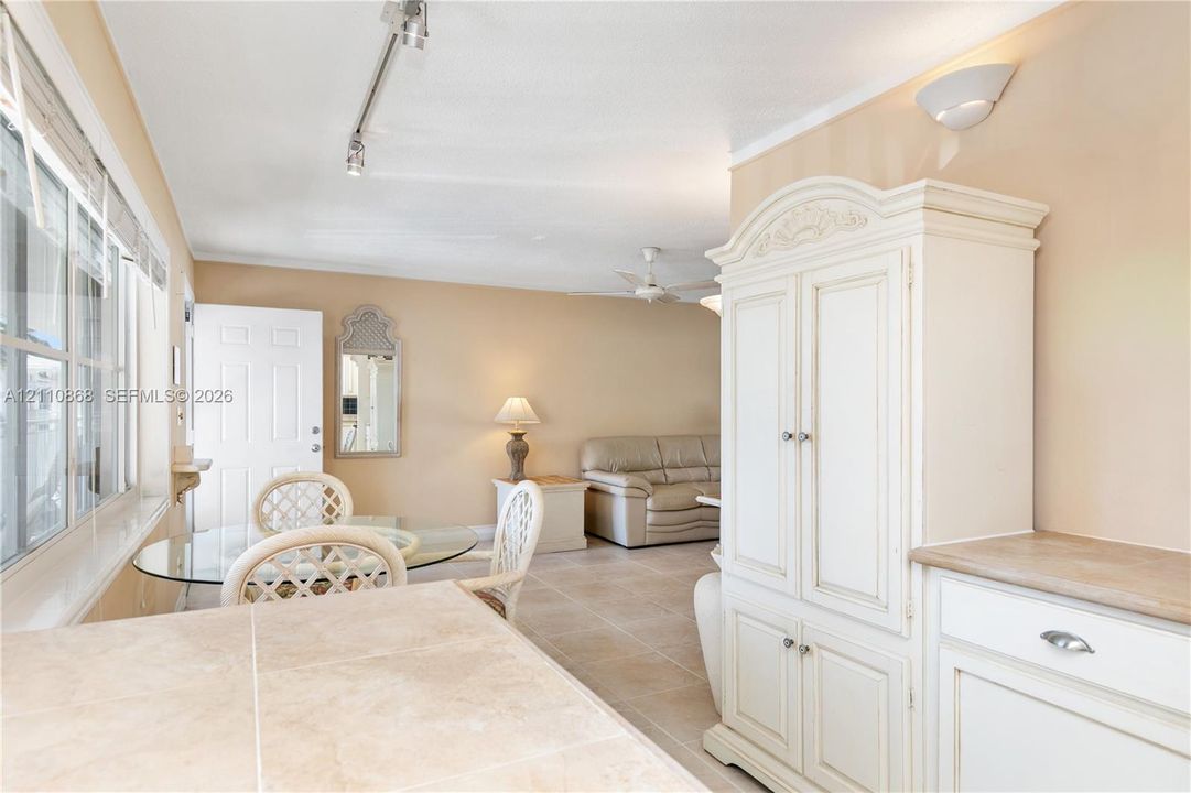 Interior featuring large-format tile flooring, built-in white cabinetry with stone-surface countertop, multi-pane windows, and track lighting