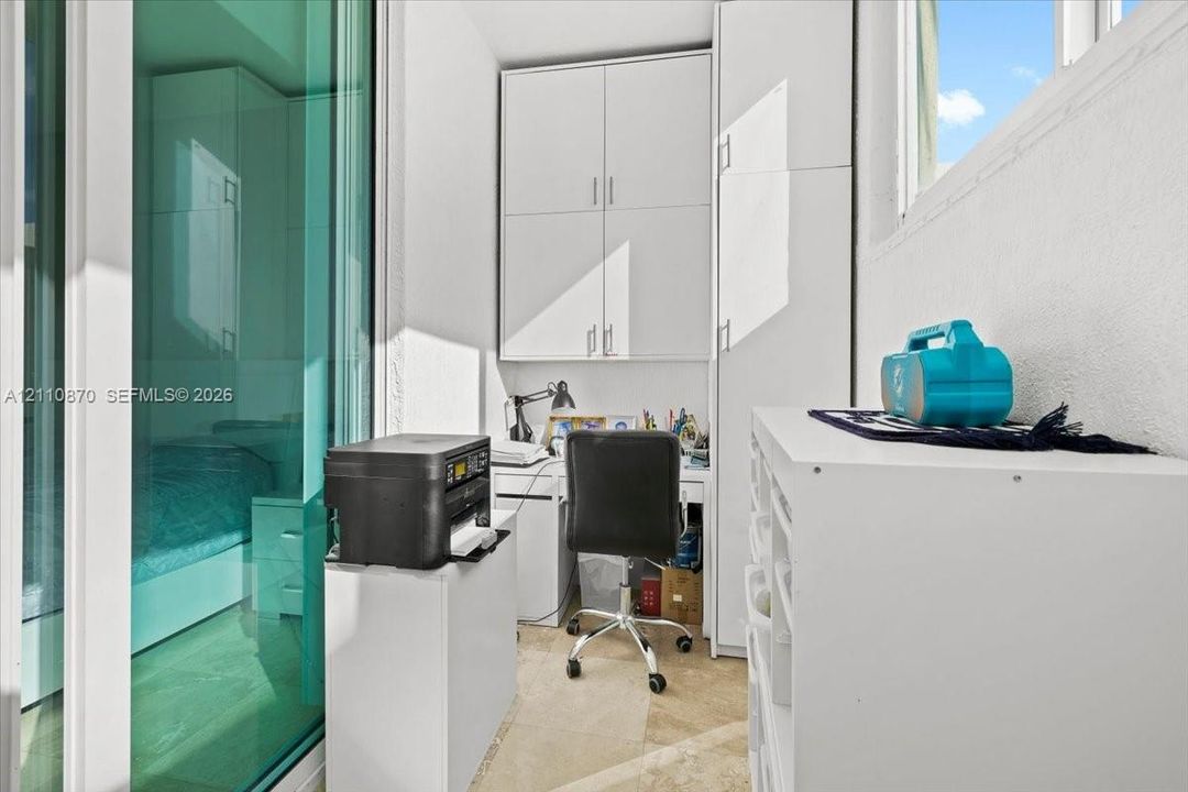 Built-in floor-to-ceiling white cabinetry, tile flooring, and sliding glass panel door