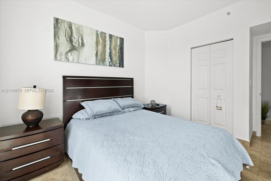 Neutral-toned interior space featuring light-colored stone-finish flooring and a double-door closet with recessed panel detailing