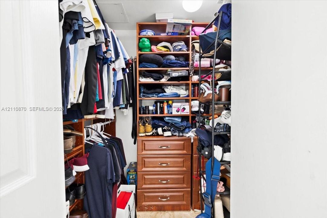 Walk-in storage space featuring built-in wood-finish shelving and a stack of four integrated storage drawers