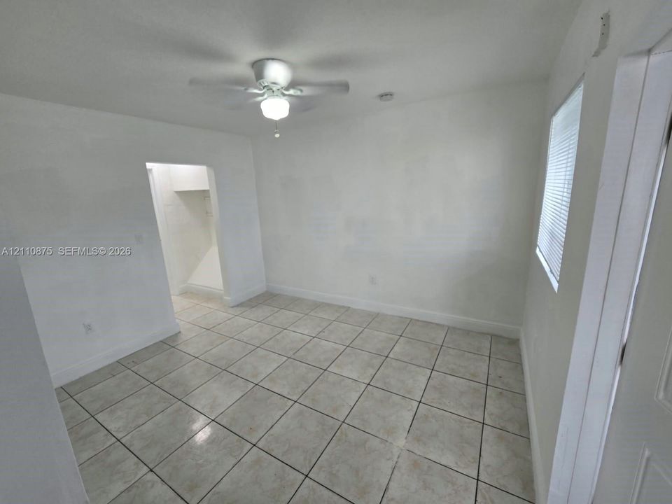 Neutral interior space featuring ceramic tile flooring, a white ceiling fan with integrated light fixture, and horizontal blind window treatments