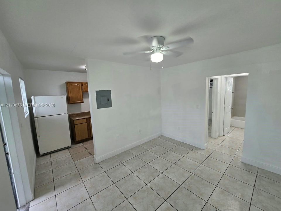 Interior space featuring tile flooring, ceiling fan with integrated lighting, and white cabinetry