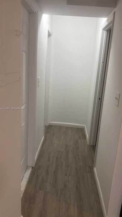 Hallway featuring white interior doors and wood-finish flooring