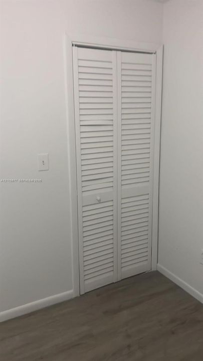 White louvered bifold closet doors with wood-finish flooring