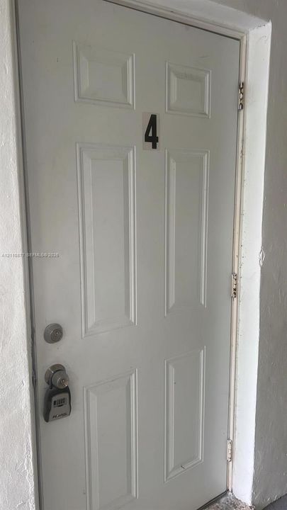 White six-panel entry door featuring a dual-lock system and door-mounted number plate