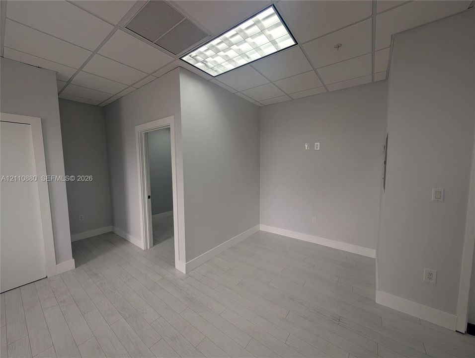 Interior space featuring wood-finish flooring, a suspended acoustic tile ceiling, and recessed lighting panels
